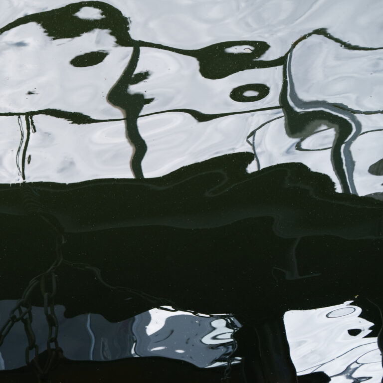 Dark water surface with pale reflections, a near-monochrome abstract study