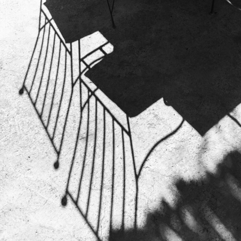 Wire chairs and their shadows on snow, seen from above, black and white