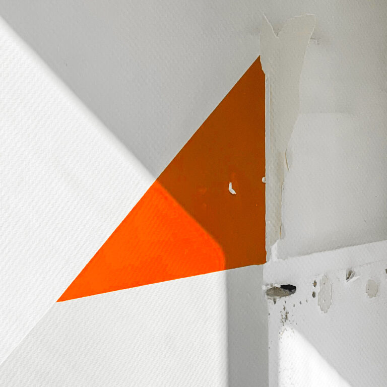 Orange triangle of light on a white wall in an empty room